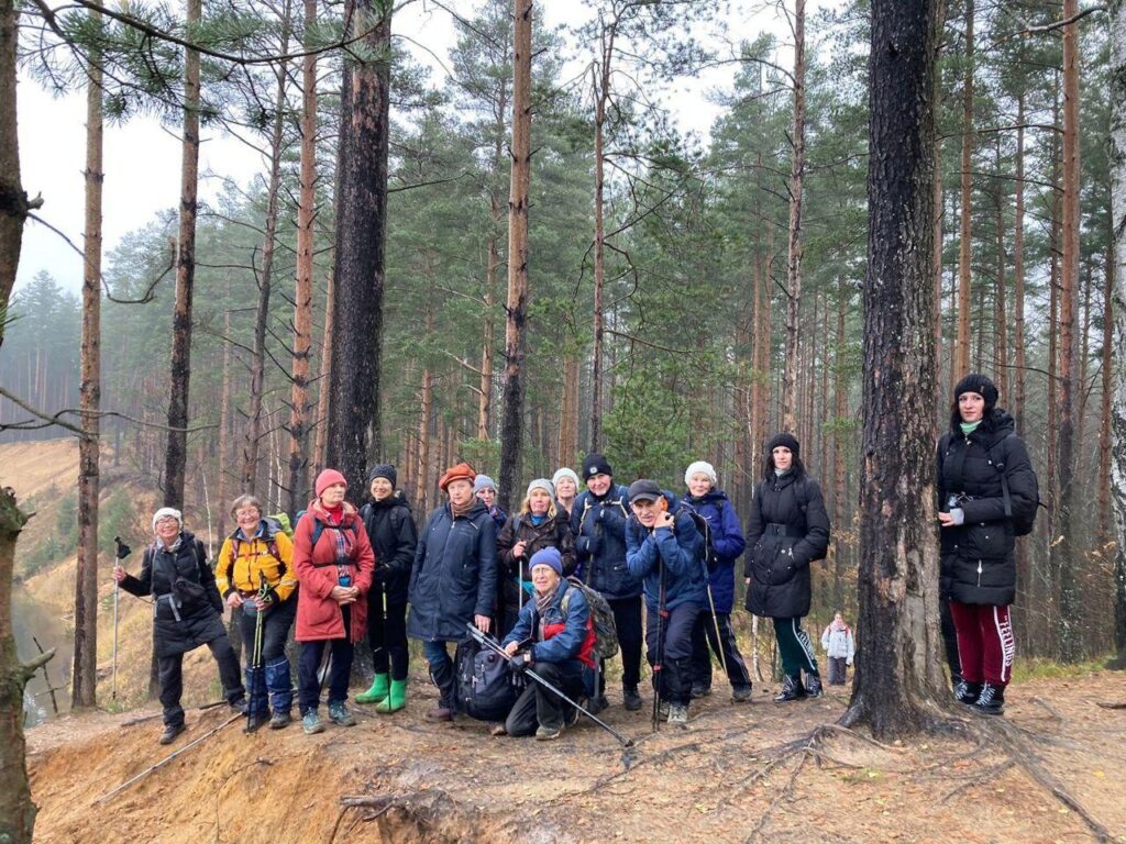 группа занимающихся с палками для ходьбы на фоне леса